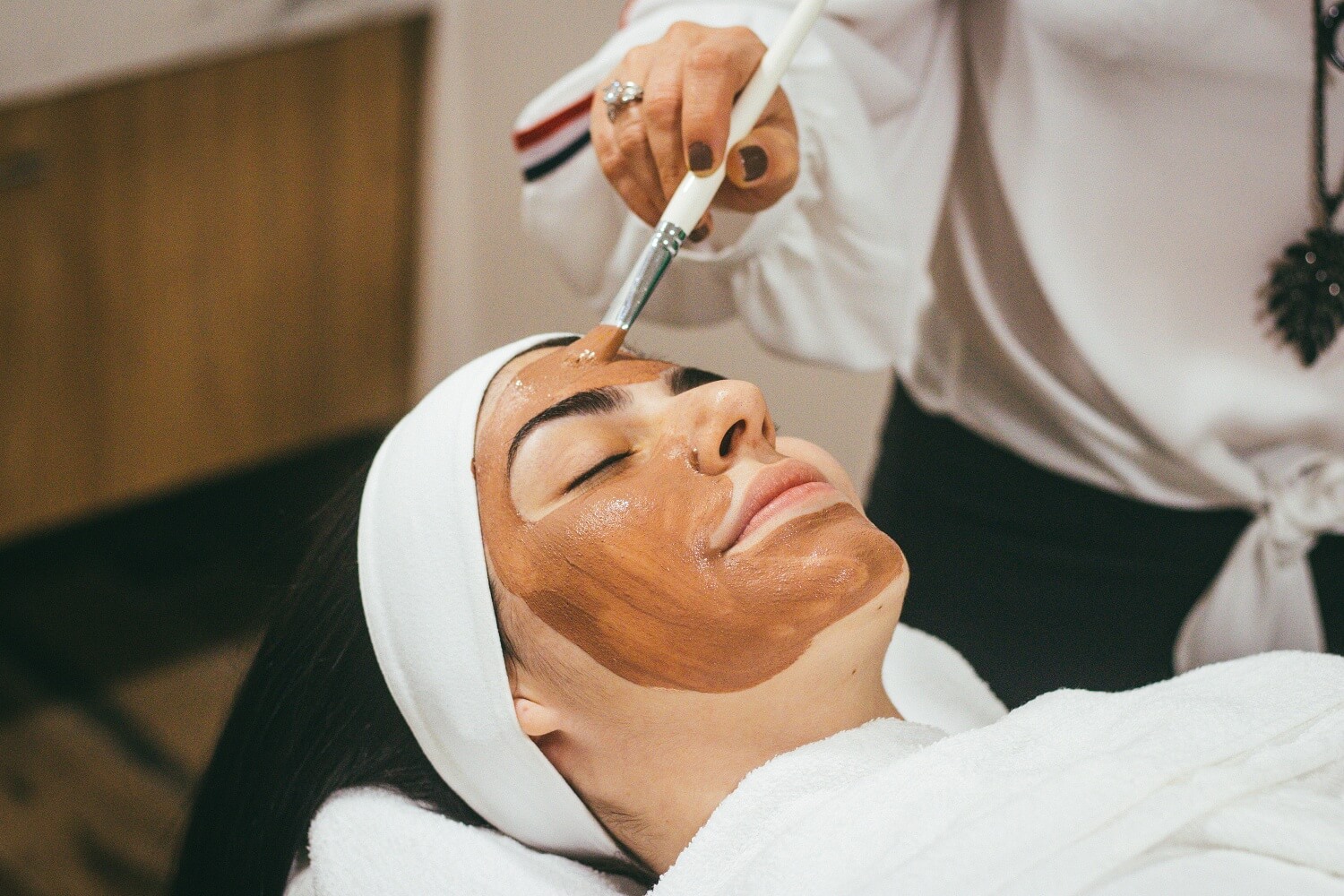 Kobieta otrzymująca zabieg na twarz w salonie kosmetycznym